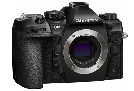 На изображении представлена беззеркальная камера OM System OM-1 Mark II Body в чёрном корпусе. Видна передняя часть камеры с открытым байонетом для крепления объектива. В верхней части отчётливо виден логотип «OM SYSTEM», слева обозначена модель «OM-1»
