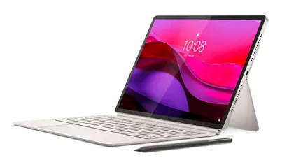 На изображении представлен планшет Lenovo Yoga Tab Plus в светло-сером корпусе. Устройство установлено в положении «тент» (с опорой на встроенную подставку). К планшету подключена съёмная клавиатура светло-серого цвета. Рядом с планшетом и клавиатурой лежит стилус