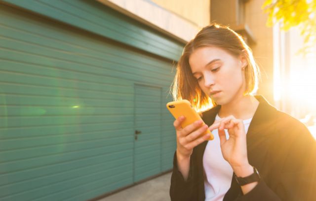 Портрет деловой девушки со смартфоном в руках в лучах солнца