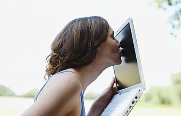 Девушка целует экран ноутбука