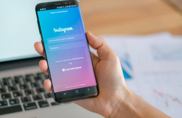 Рука бизнесмена держит смартфон с запущенным приложением Instagram